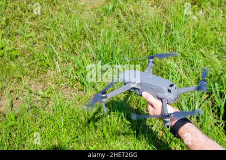 Man holding a drone before flying with green grass on the background.  Stock Photo