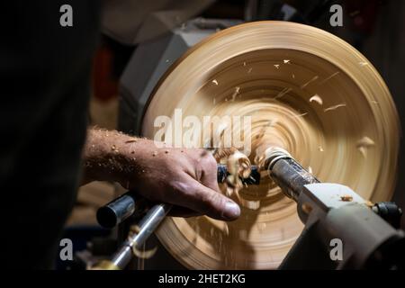 making a hole into a wooden bowl on turnery machine with chisel Stock Photo