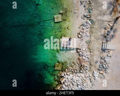 Two people eating breakfast, camping right at the ocean in Split, Croatia at Kasjuni Beach. Aerial drone view. Stock Photo