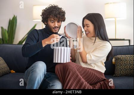 Woman opening gift and surprised man looking at card Stock Photo
