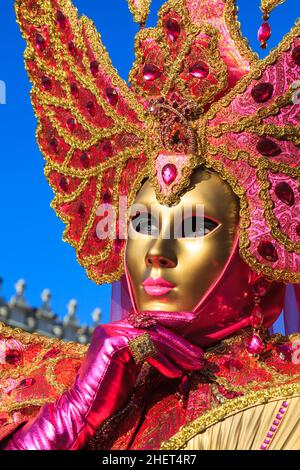 Woman in colourful pink and gold mask and historic fancy dress costume, close up portrait, Venice Carnival, Carnevale di Venezia, Italy