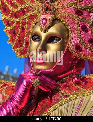 Woman in colourful pink and gold mask and historic fancy dress costume, close up portrait, Venice Carnival, Carnevale di Venezia, Italy