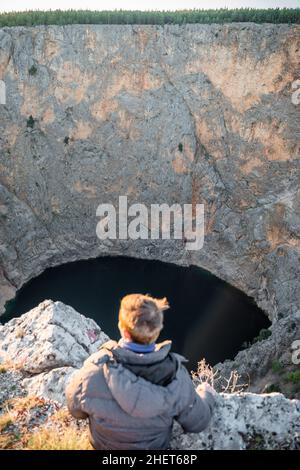 Blond guy relaxing at red lake in April at Imotski, Dalmatia, Croatia Stock Photo