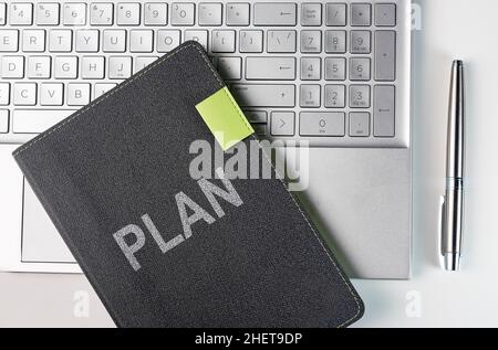 Plan word on business planner notebook on laptop keyboard and pen of silver color, top view. Stock Photo
