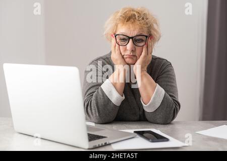 An elderly woman fills a receipt for payment of utility bills. Stock Photo