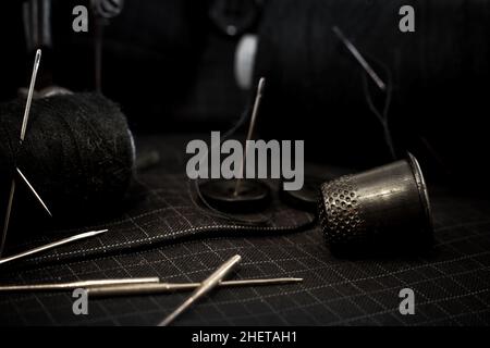 Old retro sewing machine, needle with thread, scissors and thimble. Tailor, seamstress and fashion designer tools for sewing clothes. Handmade Stock Photo