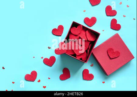 Open gift box and knitted hearts on blue background, top view. Valentines day greeting card. Flat lay style. Stock Photo