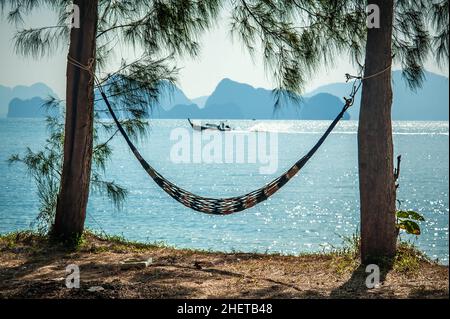 Hammock between two exotic trees at tropical beach background. Paradise vacation in Thailand Stock Photo