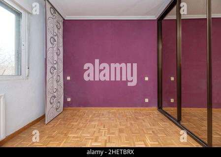 Bedroom with built-in wardrobe with sliding mirrored doors with window and curtains Stock Photo