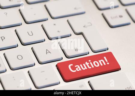 computer keyboard with the word caution on red key Stock Photo