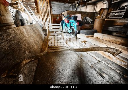 storage room in old barn with old moped and wooden barrow Stock Photo