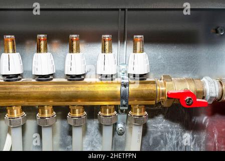 New brass manifold for underfloor heating systems with rotameters  indicate flow of 0 liters per minute, open red valve. Stock Photo