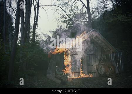 old burning wooden hut standing at forest Stock Photo