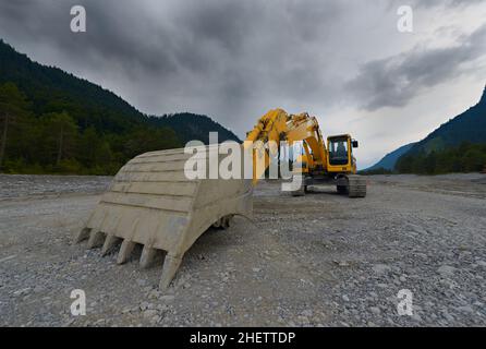 orange mechanical shovel excavator or bucket digger on gravel Stock Photo