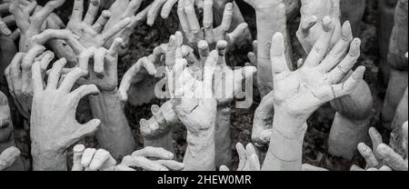 WAT RONG KHUN - WHITE TEMPLE, CHIANG RAI THAILAND - CIRCA MAY 2018. The sculpture of hundreds outreaching hands that symbolize unrestrained desire. Stock Photo