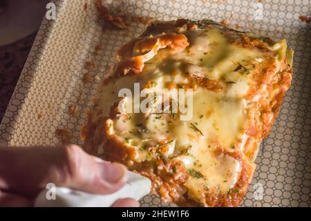 lasagna in an aluminum pan, spatula taking a piece of the pan, selective  focus Stock Photo - Alamy