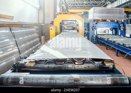 Ready for distribution packaged metal roof tile sheets on automation production line or conveyor belt in modern metalwork factory. Stock Photo