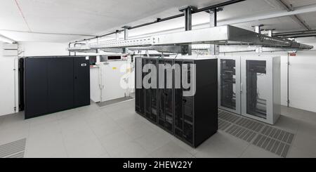 wide angle view of small air conditioned computer room with racks an cable trays Stock Photo