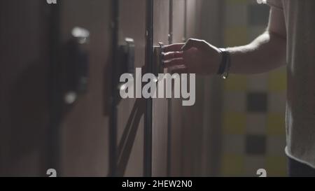 Man's hand opening locker with electric key on his wrist at gym in the changing room. Close up hand opening the locker door in the changing room of a Stock Photo