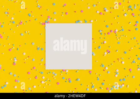 Colorful sprinkles with a paper white blank card on a yellow background Stock Photo