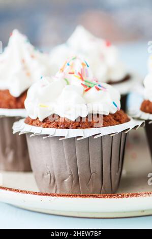 Carrot cake cupcakes with cream cheese frosting with sprinkles. Close up. Stock Photo