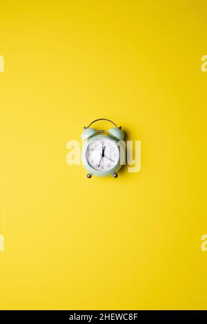retro circular clock on a plain yellow vertical background, ring sound Stock Photo