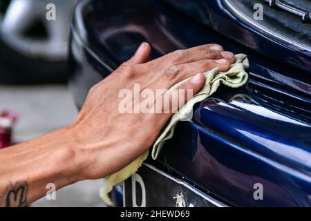 Man hand polish a blue car exterior with duster to get clean , shine and detail surface on the automotive garage. Suitable for paint work and detailin Stock Photo