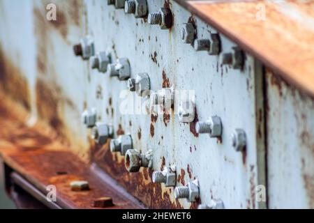 Line of Bolts and Nuts make an industrial arrangement on big and heavy metal bridge piling with white rustic texture at construction site Stock Photo