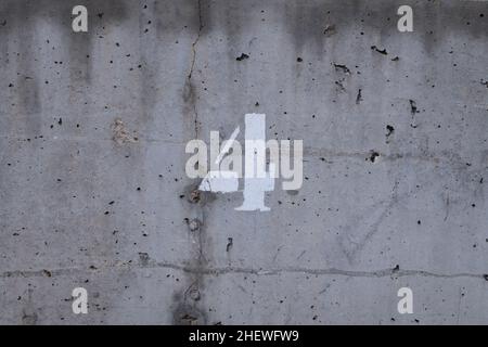 number four over a concrete wall with black dots and a fissure Stock Photo