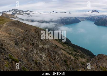 Beautiful view of Garibaldi Lake from Panorama Ridge hike in British Columbia, Canada. Mountains and glaciers peeking through the clouds in the backgr Stock Photo