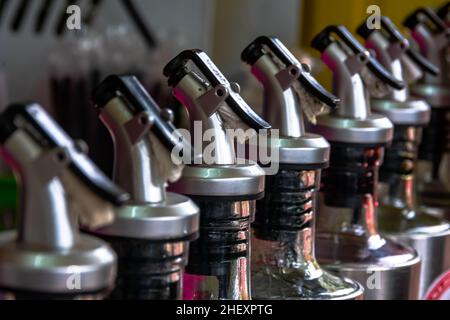 line of professional stainless steel bottles cap of syrup from the street food bar vendor Stock Photo