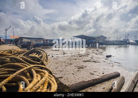 Sandakan, Malaysia - January 06, 2022: Fisher man village near the center of Sandakan, Borneo. Poor huts on stilts over the coast water on the shore. Stock Photo