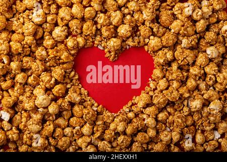 love concept image of heart shape frame made of caramel popcorn on red background Stock Photo