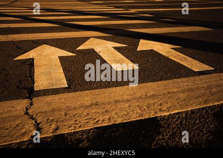 Pedestrian crosswalk on the evening street in warm evening light. Three arrows indicate the direction of crossing. Stock Photo