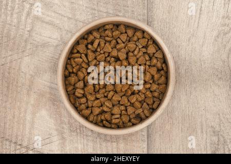 Dry pet food in ceramic bowl on wooden floor. Dog or cat pets food. Stock Photo