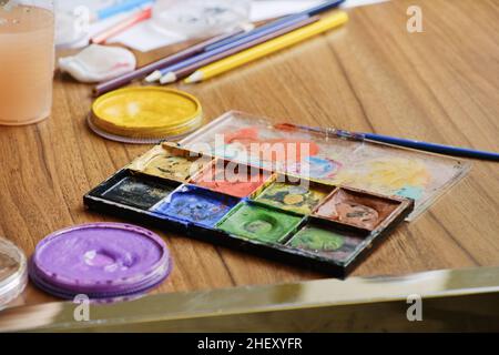 Artistic tools for drawing paintings on wooden table. Palette, watercolor, brushes, colored pencils. Stock Photo