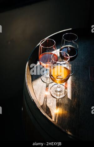 Glass of Porto wine on a wooden oak barrel with long shadow in moody atmosphere Stock Photo