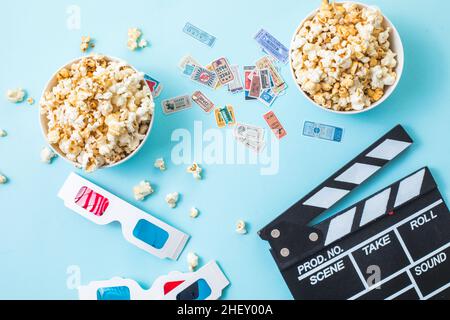 Cinema minimal concept. word movie, popcorn, clapperboard, 3D glasses and tickets top view flat lay on blue background Stock Photo