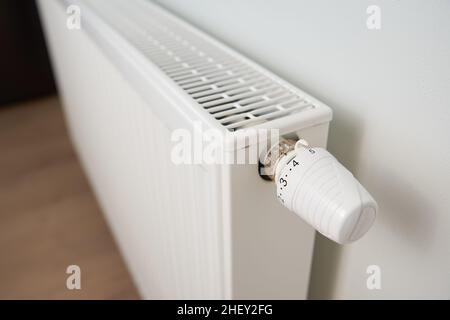 Adjusting temperature on heating radiator thermostat, Turning heat radiator knob to control heat in home Stock Photo