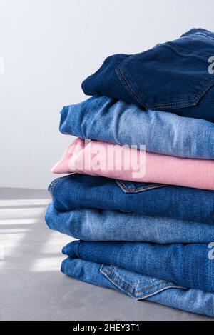 a pile of blue and pink jeans on a gray background. Close up Stock Photo