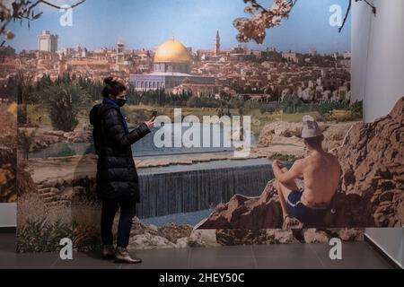 A visitor takes photo with cellular phone of three dimensional photography printing entitled 'The view is spectacular, at night its cold' by David Barell and Keren Zaltz depicting large print of postcards from the sixties and seventies showing Israel's landmarks displayed at Beita art gallery in West Jerusalem, Israel.