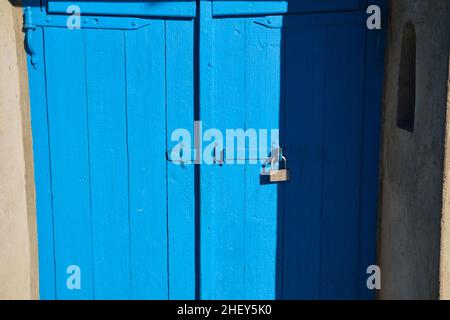 ancient blue painted wooden gate with a lock on the right side Stock Photo