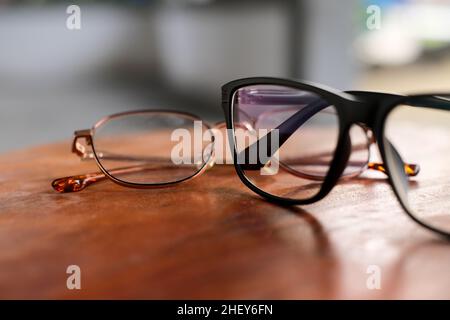 On a wooden background lie photochromic sunglasses with a black frame and a Summer gold frame. Accessories. background. abstract Stock Photo