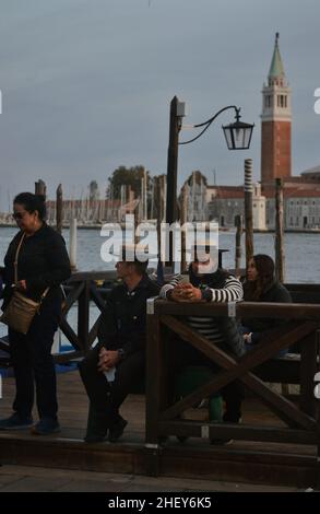 gondoliers and tourits on a work break on a mooring station. Gondola is a major mode of touristic transport in Venice Stock Photo