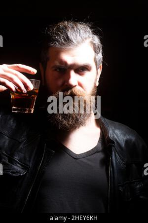 Man drinking whiskey, brandy, cognac. Man with glass of brandy. Bearded hipster with glass of whiskey. Old traditional whiskey drink - gentlemans Stock Photo
