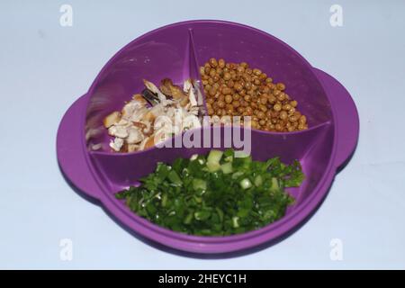 chopped green onions, fried soybeans, shredded chicken placed in a purple bowl served as a side dish Stock Photo