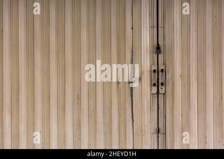 Yellowed old and dull color from the locked garage sliding and folding door of the closed store front Stock Photo