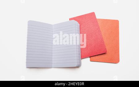 Notepad isolated on white background. Open copybook, blank paper page on red and orange color hardcover notebook, School supply, Stock Photo