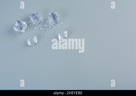 Five ice cubes in melted water on a gray background Stock Photo
