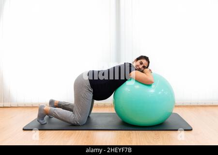 A pregnant woman doing breathing exercises and resting on a fitness ball Stock Photo